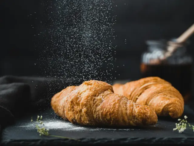 Croissants under a fall of icing sugar.